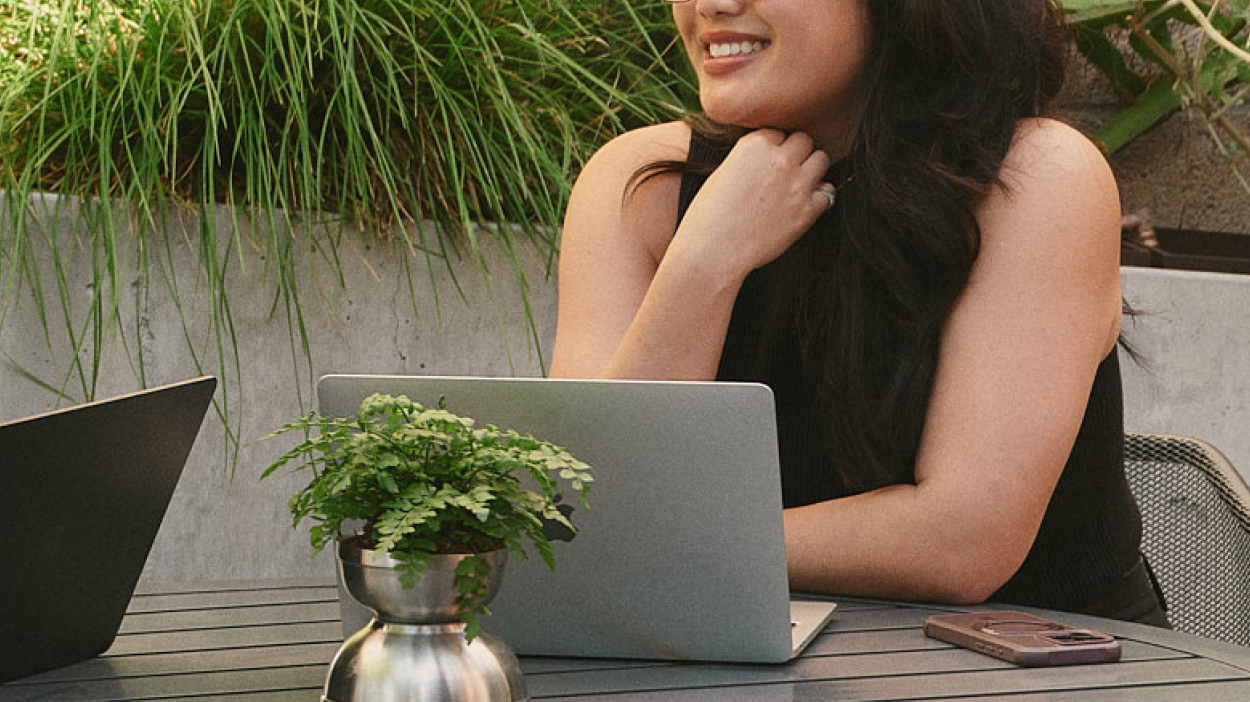 Person working on a laptop on a table outside.